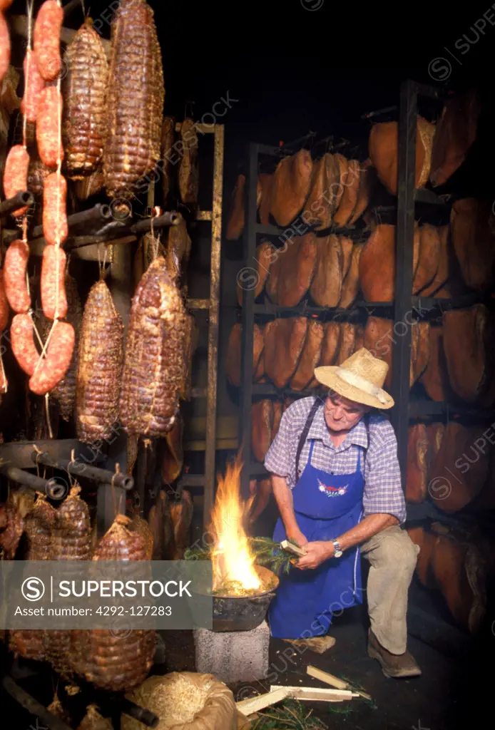 Italy, Trentino Alto Adige, Sarentino Valley, Man Smokery the Speck Hams.