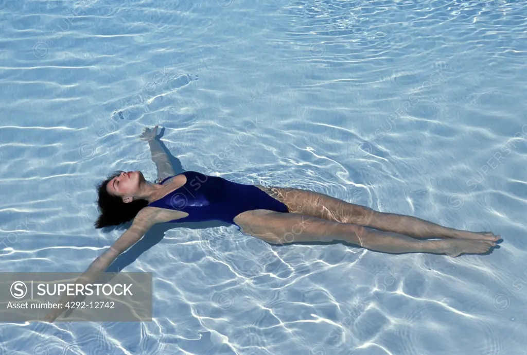 Young woman floating in water in swimming pool