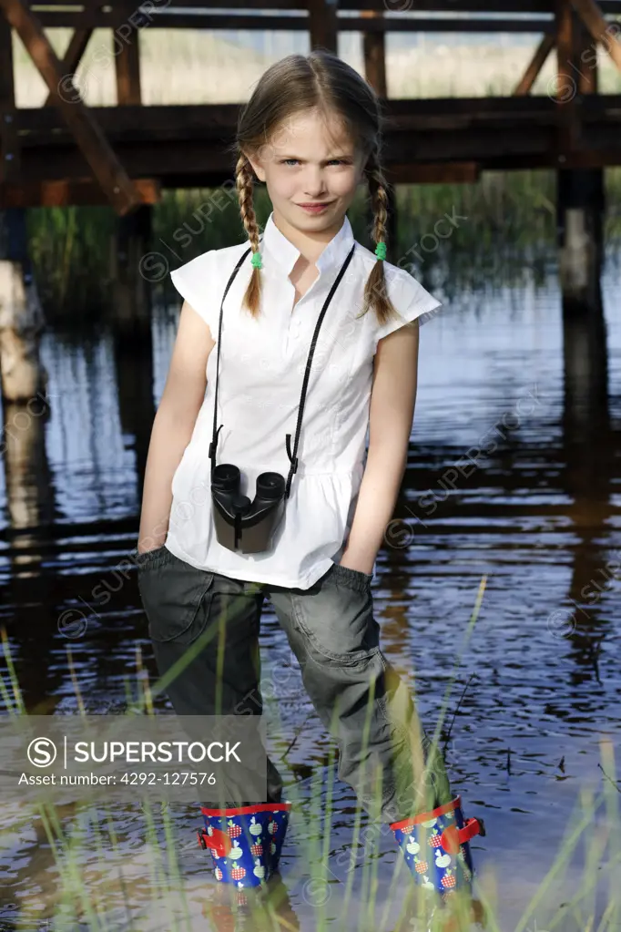 Portrait of girl with binoculars standing next to pond