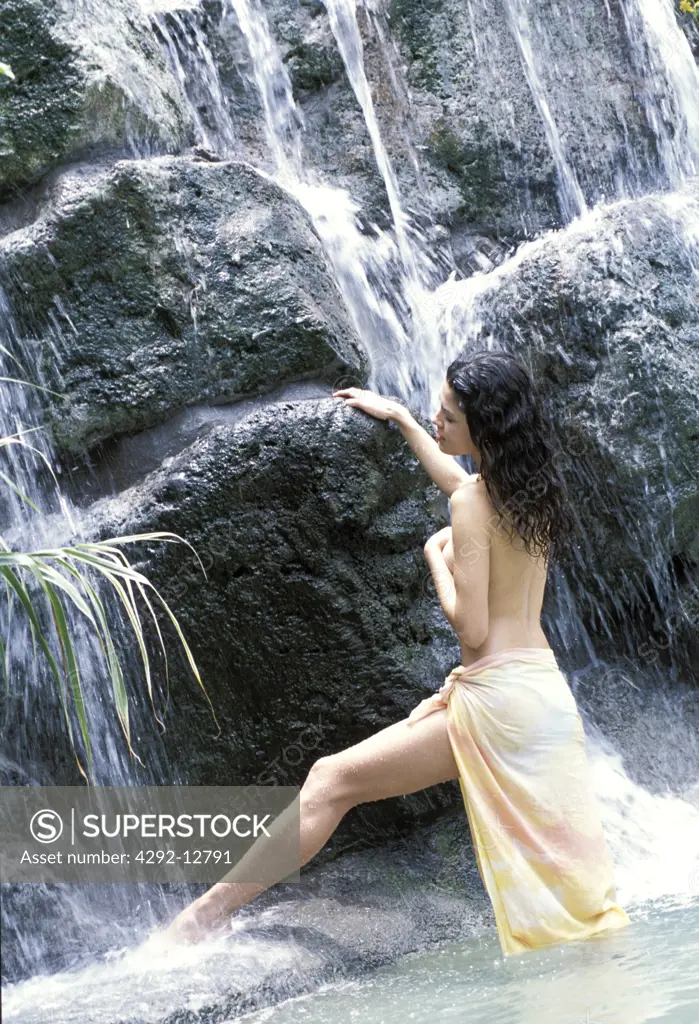 Woman standing under waterfall