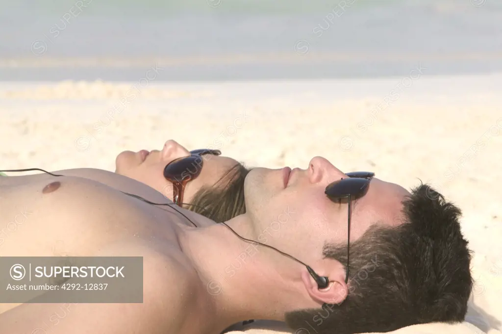 Couple lying on the beach, listening music