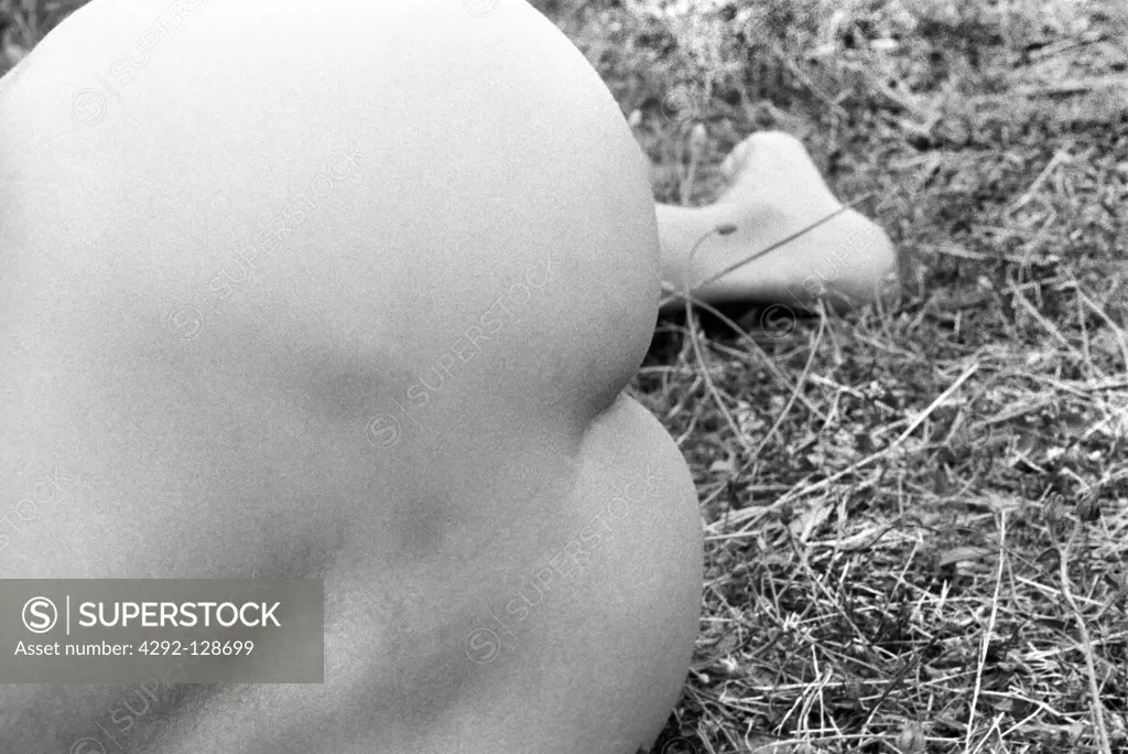 Back view of naked woman lying on grass