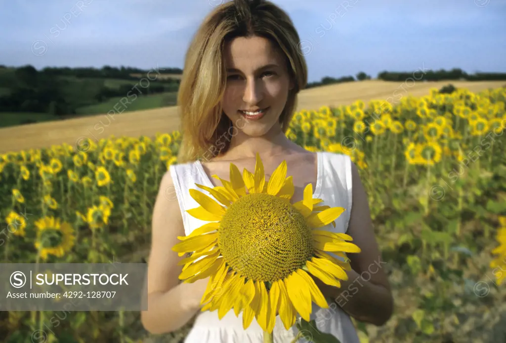 Woman standing in field holding sunflower