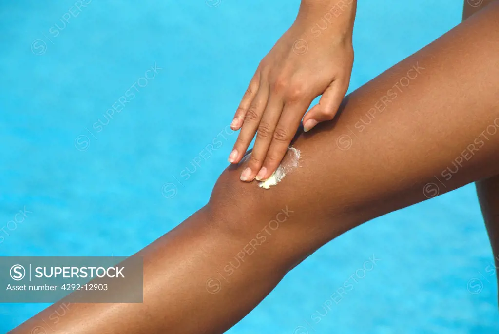 Woman applying cream on her leg, close up