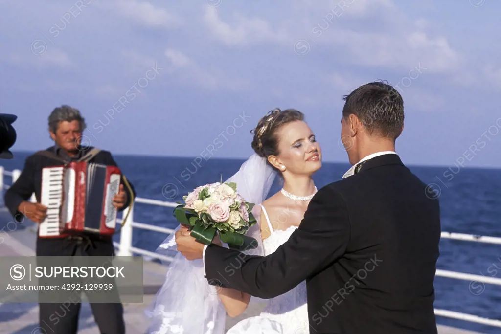 A wedding pair with the Cazino restaurant on the shore of the Black Sea in the coastal city of Constanta in Romania.