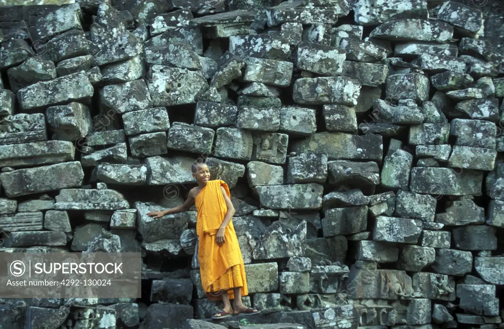 A monk before ruins to stones of the Bayon ruins in the Bayon temple in the ruins city of Angkor in Cambodia in southeast Asia.