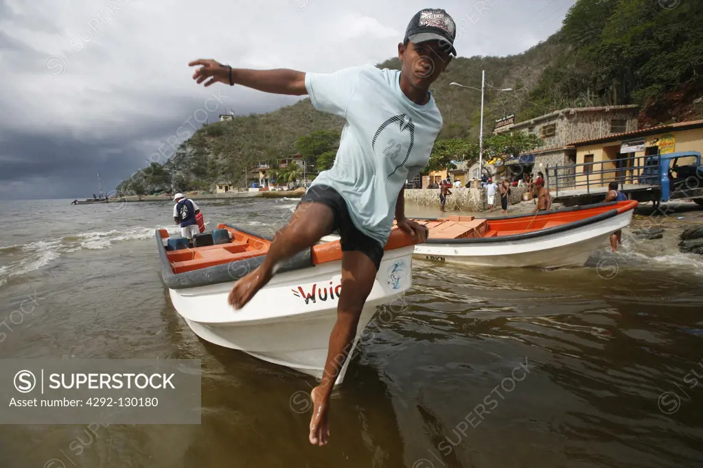 A boy jumps out of a taxi boat in Chuao in the Caribbean in Venezuela in South America.