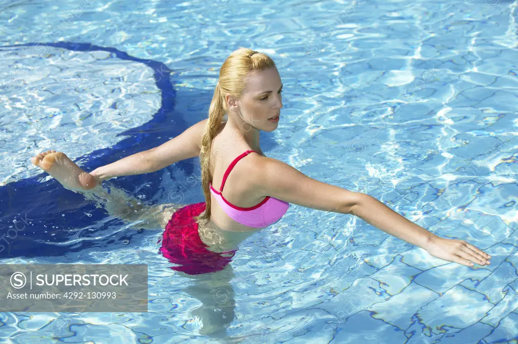 Junge Frau macht Aquagymnastik im Pool, young woman doing acqua gymnastics in the swimmingpool