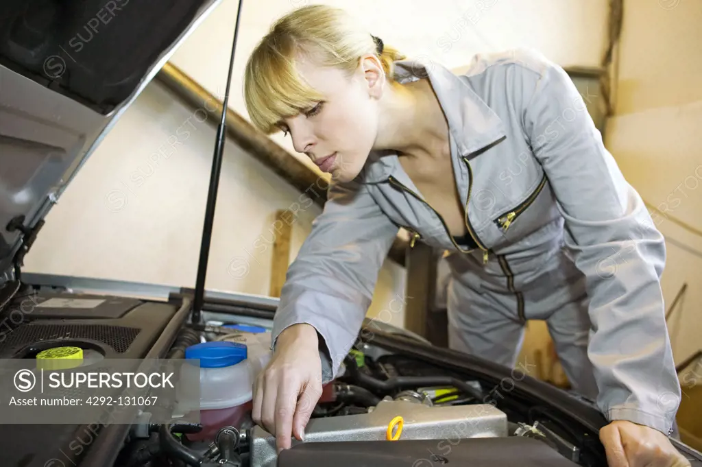 Junge KFZ Mechanikerin in der Werkstatt, young female motor mechanic at a garage