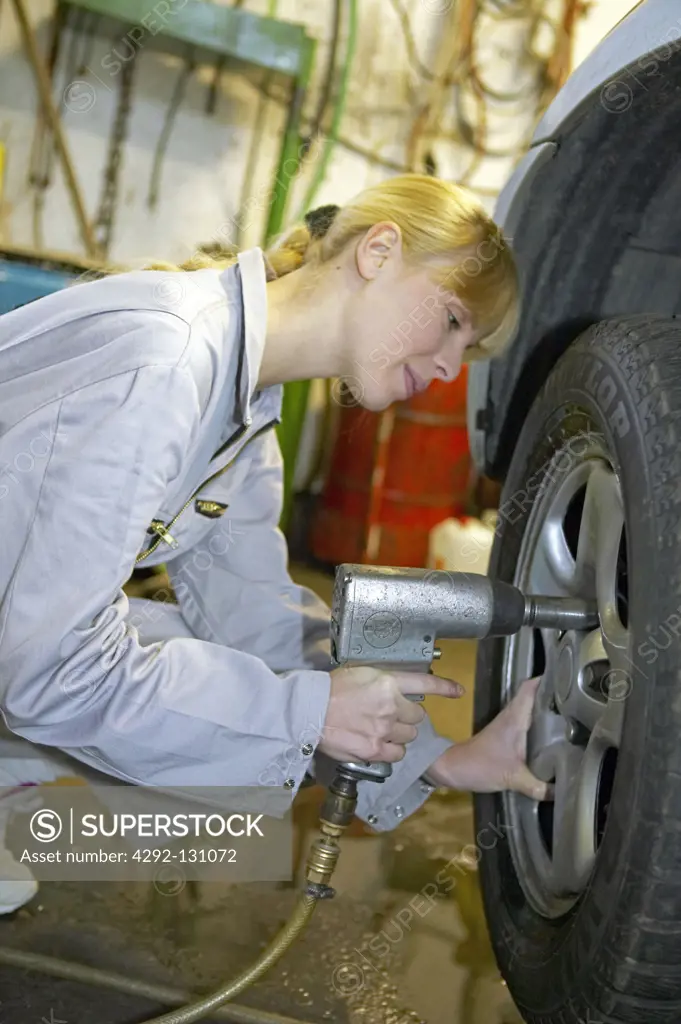 Kfz-Mechanikerin beim Reifenwechsel, female motor mechanic changing car wheel