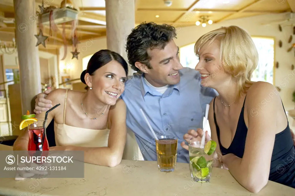 Mann flirtet mit zwei Frauen an der Hotelbar, Man flirting with two women at a hotel bar