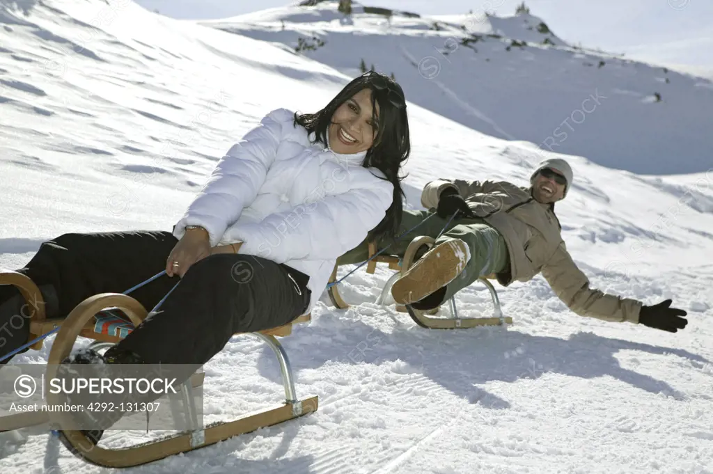 Junges Paar beim Schlittenfahren in den Bergen, Couple Sledging in Mountains Winter Holiday