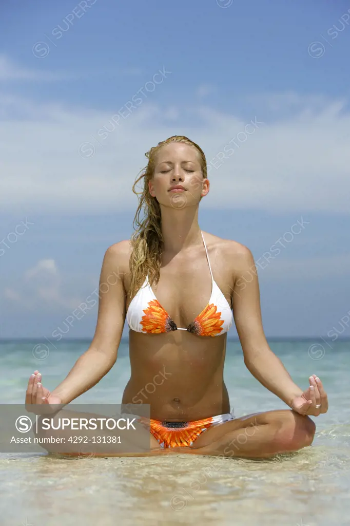 young blonde woman doing yoga on the tropical beach in