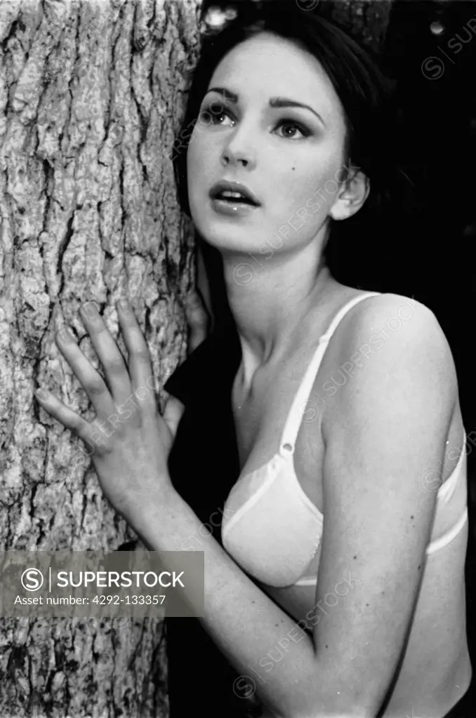 Girl leaning against a tree.