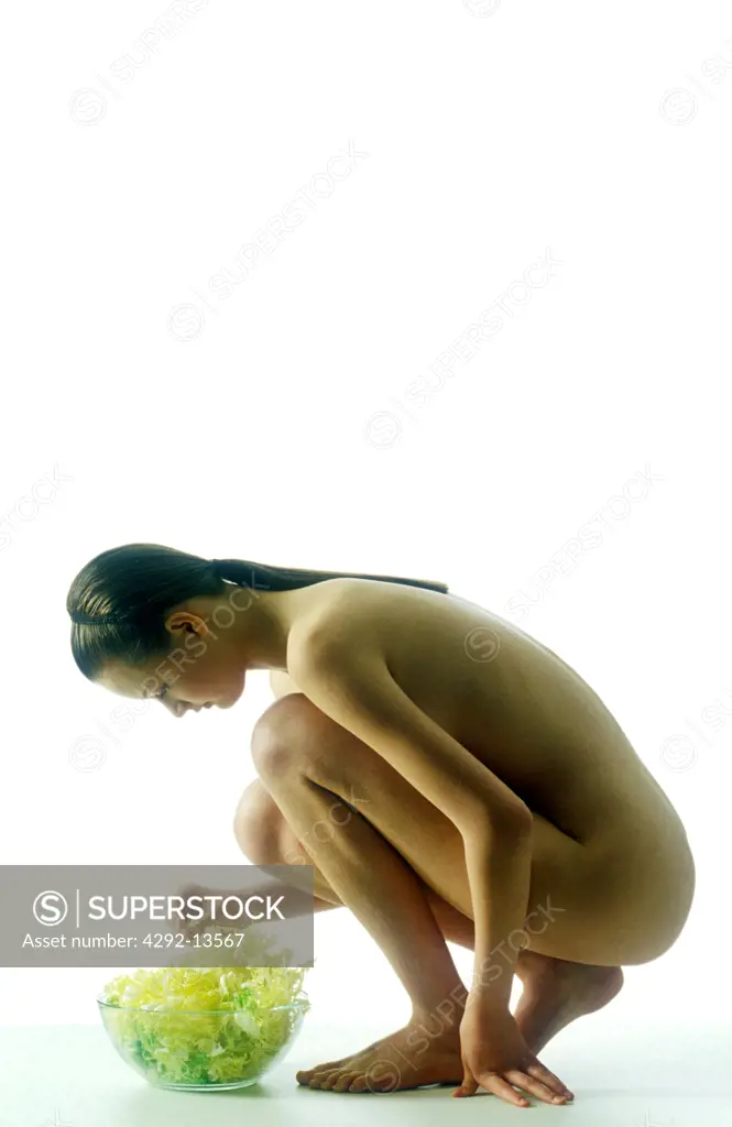 Woman nude body crouching touching salad