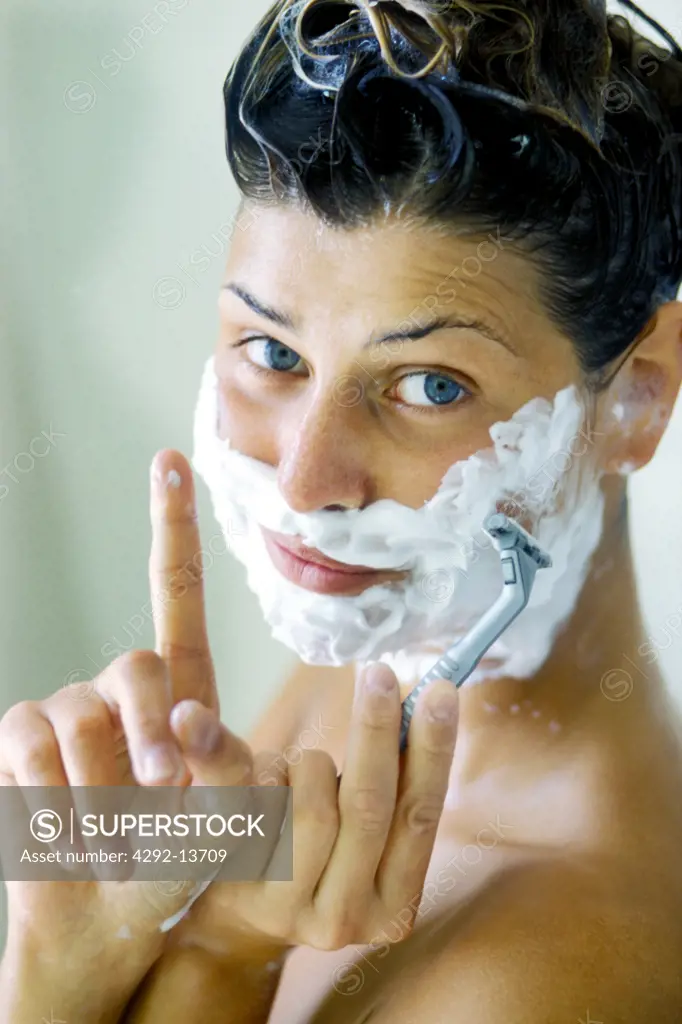 Woman with soap on her face and blade in her hand
