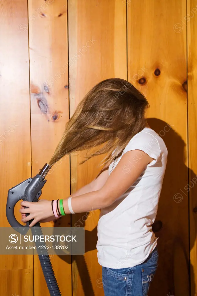 Teen girl playing with vacuum cleaner