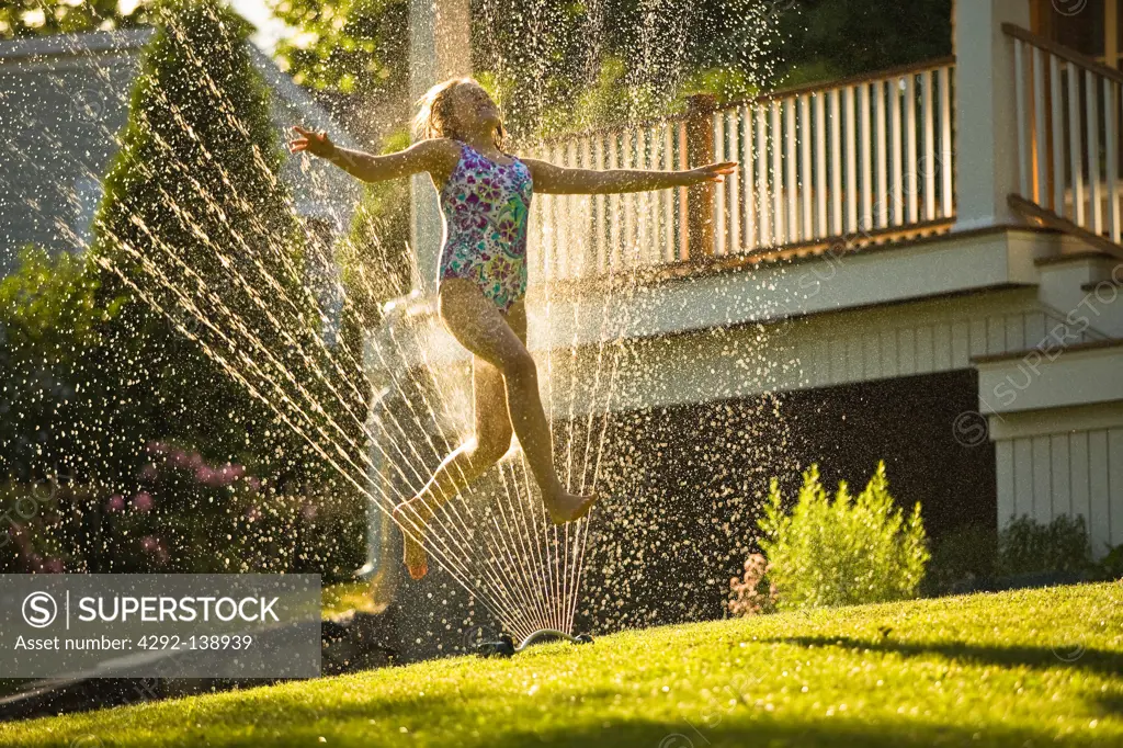 Girl under a water sprinkler