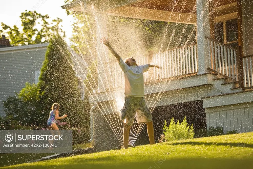 Boy and girl under a water sprinkler