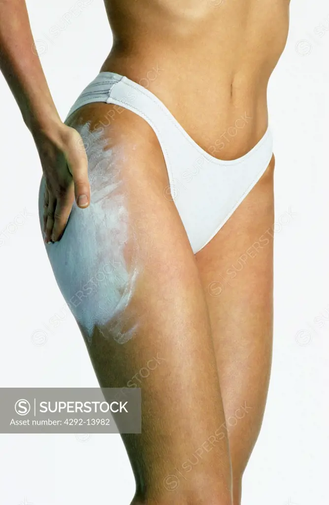 Woman spreading cream on her hip