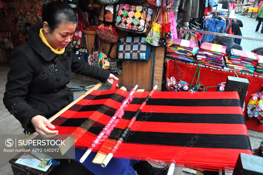Yangshou, China, a woman at the loom, weaving a cloth along the Walking Street