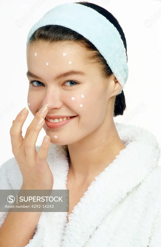 Woman spreading cream on her face