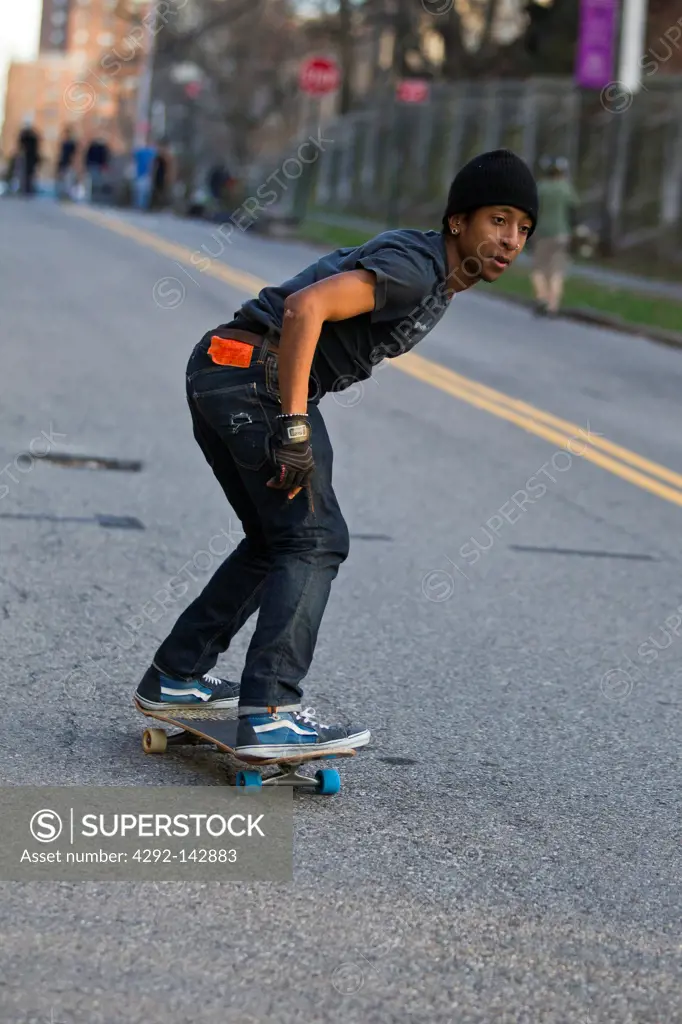 Young male skateboarder on urban street.