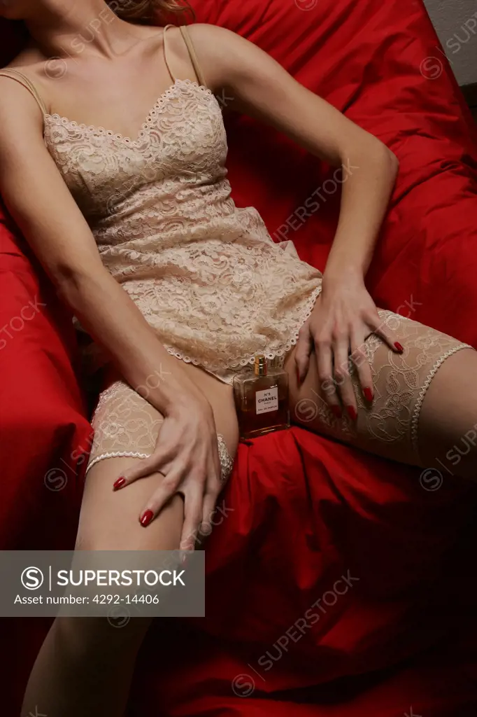 Woman in underwear with perfume bottle between her legs