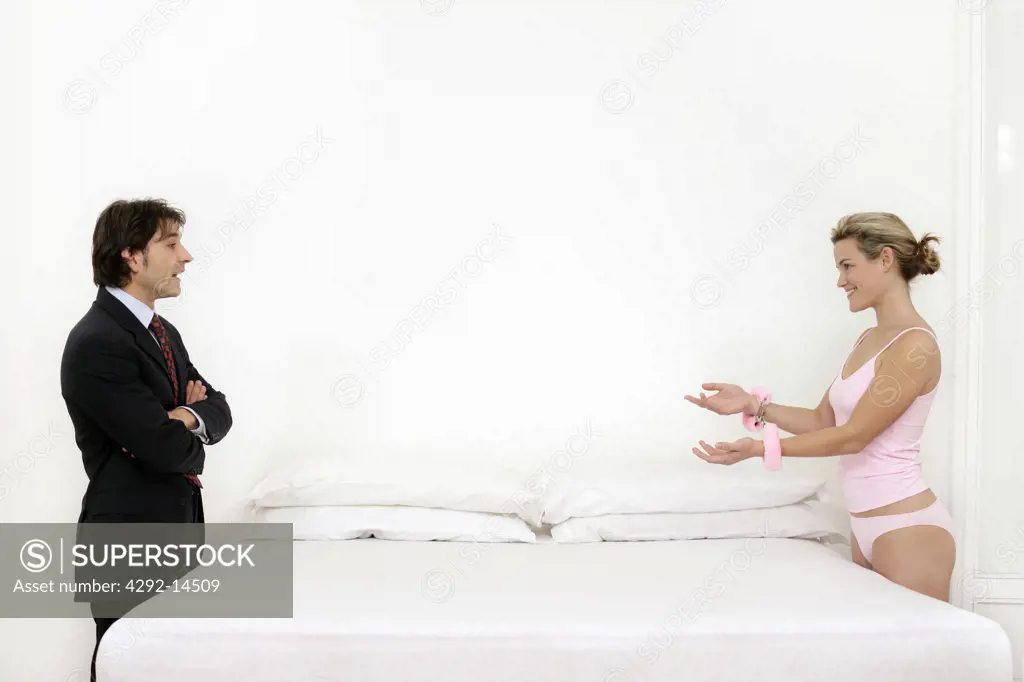 Couple standing by bed, woman with handucuffs