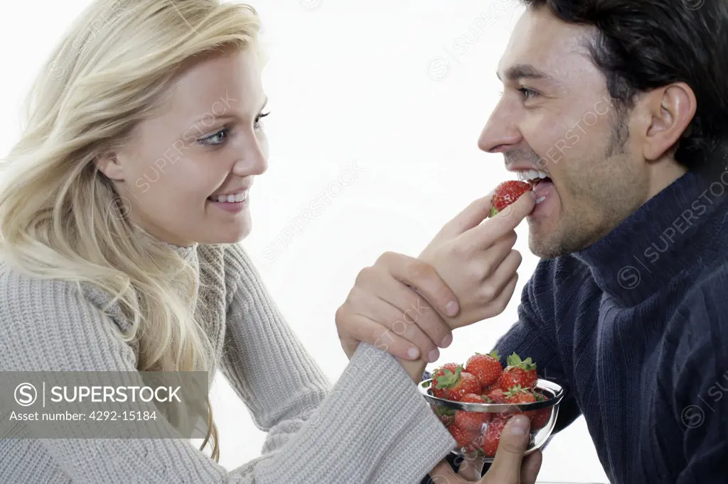 Woman feeding man with Strawberry