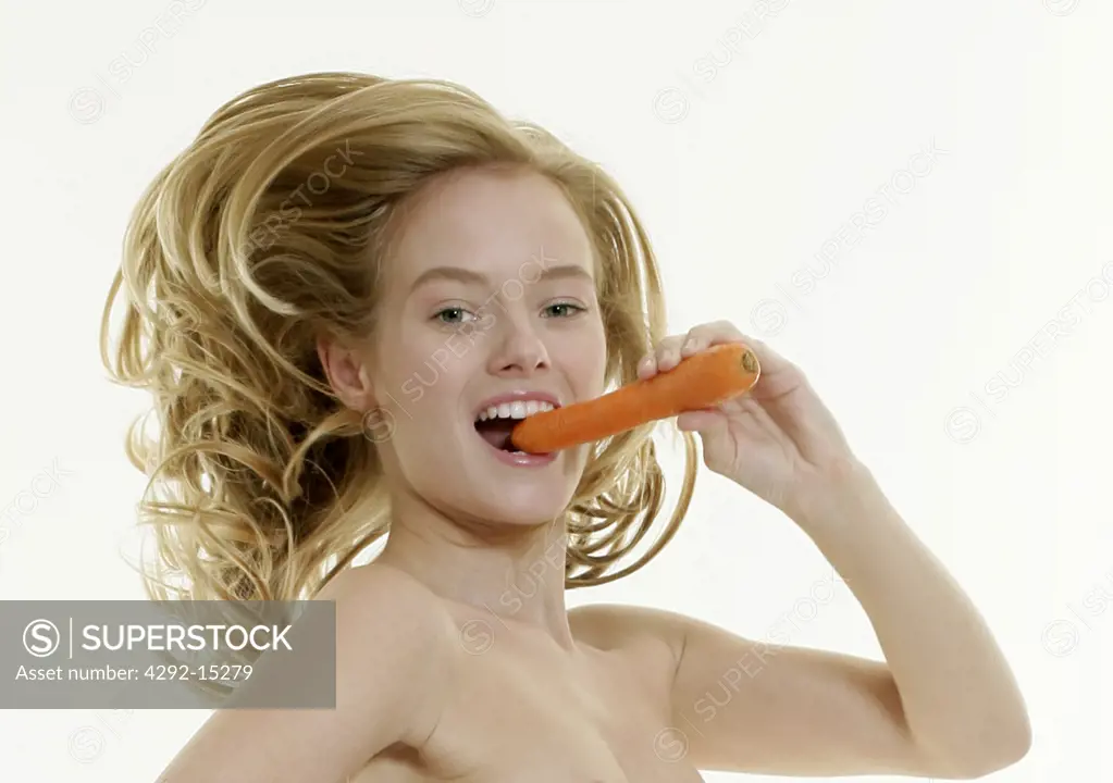 Naked woman eating carrot