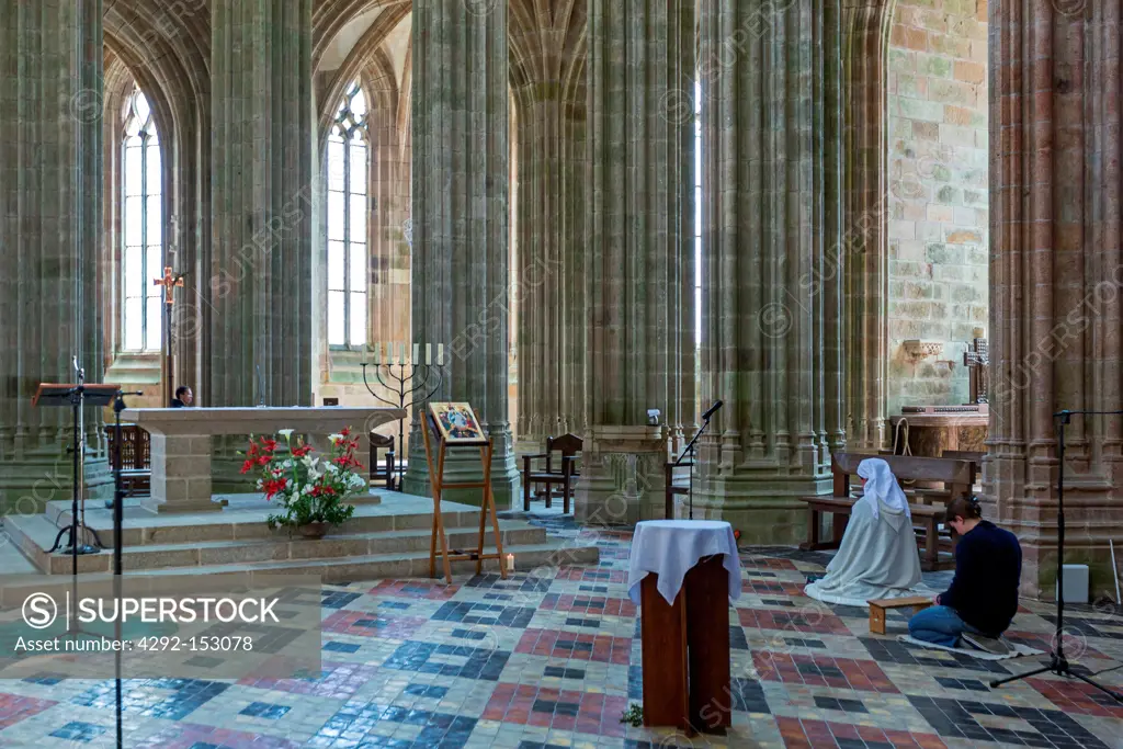 France, Normandy, Mont St Michel, a nun in prayer in the church of the abbey