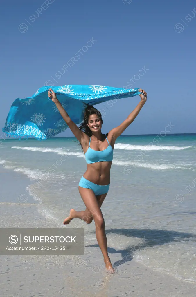 Woman in swimsuit running  on the beach