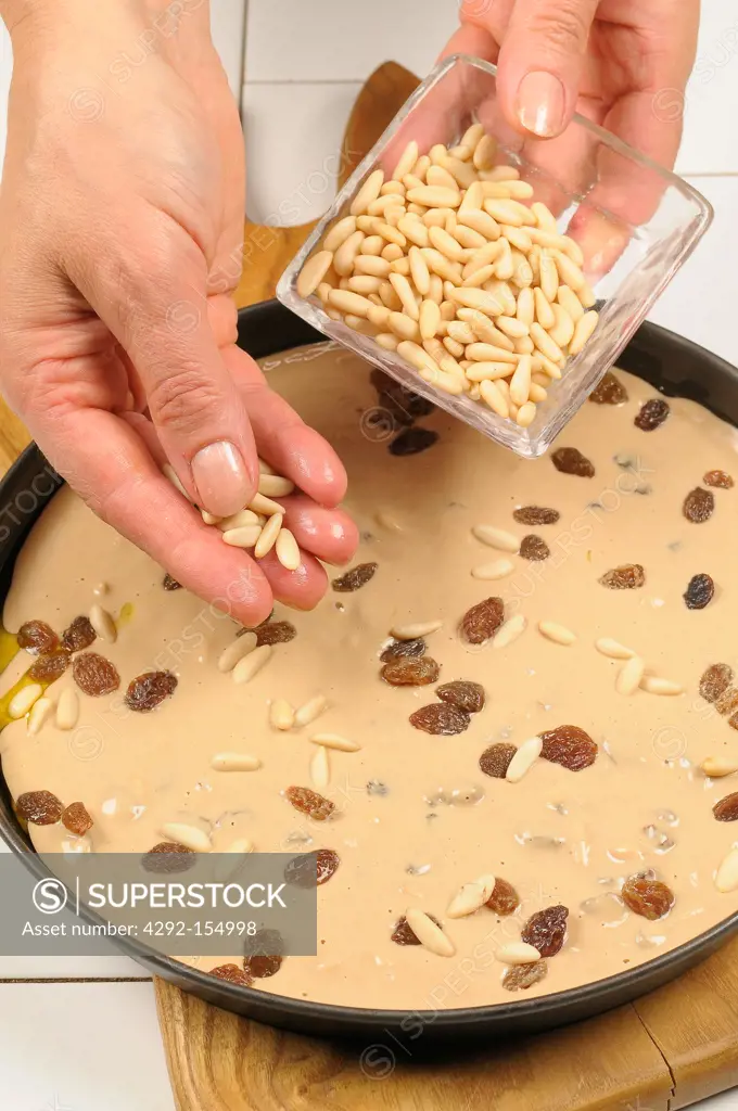 Pine nuts and raisins distributed on a chestnut cake before baking