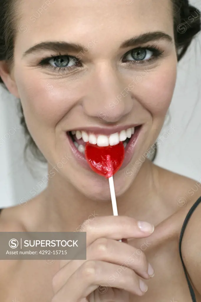 Portrait of young woman eating candy lollipop
