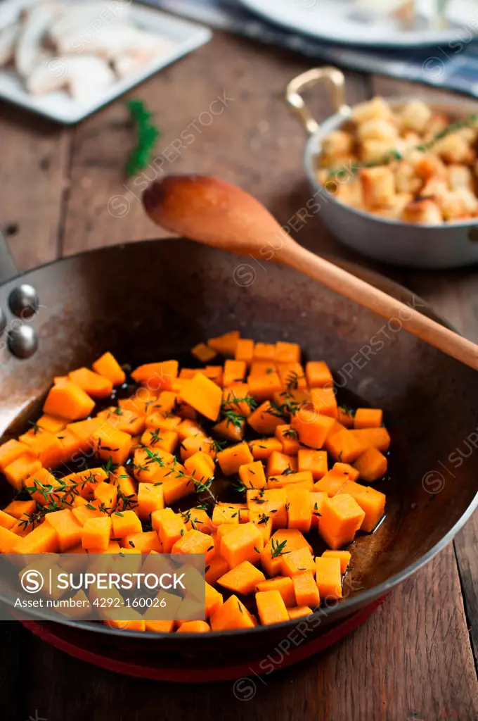cubes of pumpkin with leaves of thyme in a pan