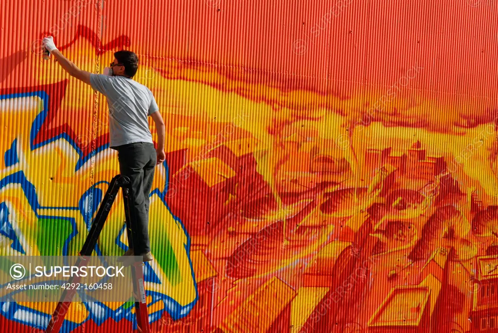 Italy, Milan, young people paint graffiti in an underpass of Bovisa district