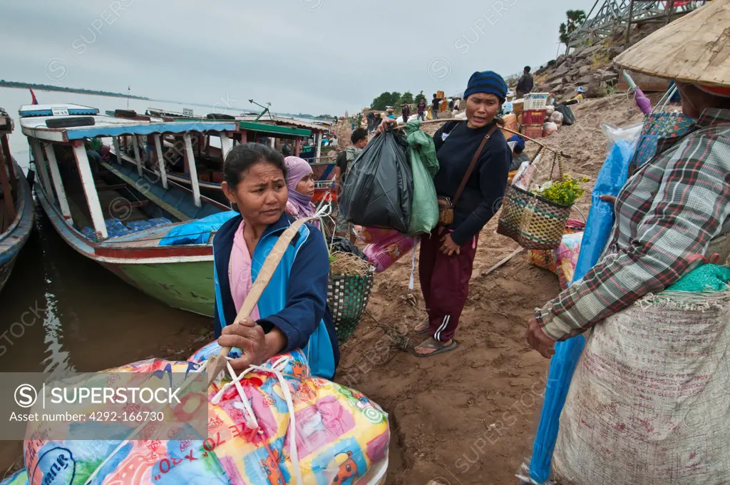Laborers loading goods into boats, to be carried accross the Mekong from Thailnad to Laos
