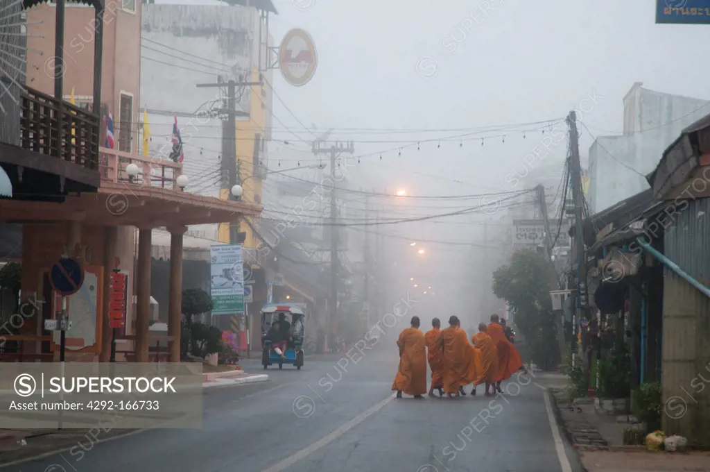 Monks going for alms early morning on the street in Nakhon Phanom, Thailand