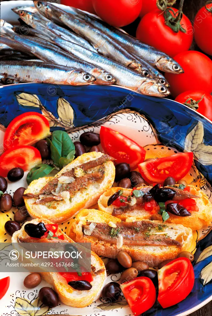 Italy, Liguria, traditional bruschette with anchovies, tomato and olives