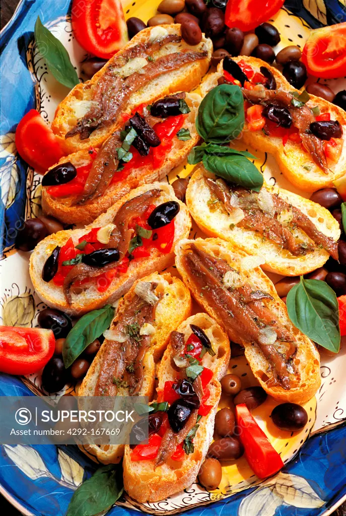 Italy, Liguria, traditional bruschette with anchovies, tomato and olives