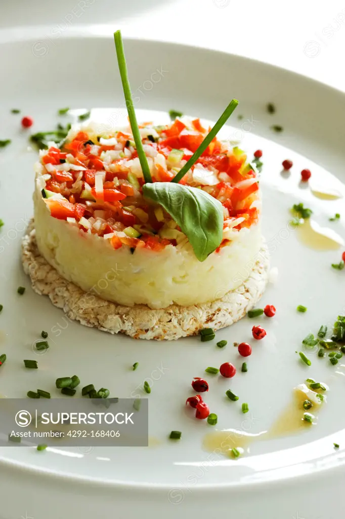 Potatoes purée on a rice cracker with fresh minced tomatoes and onion