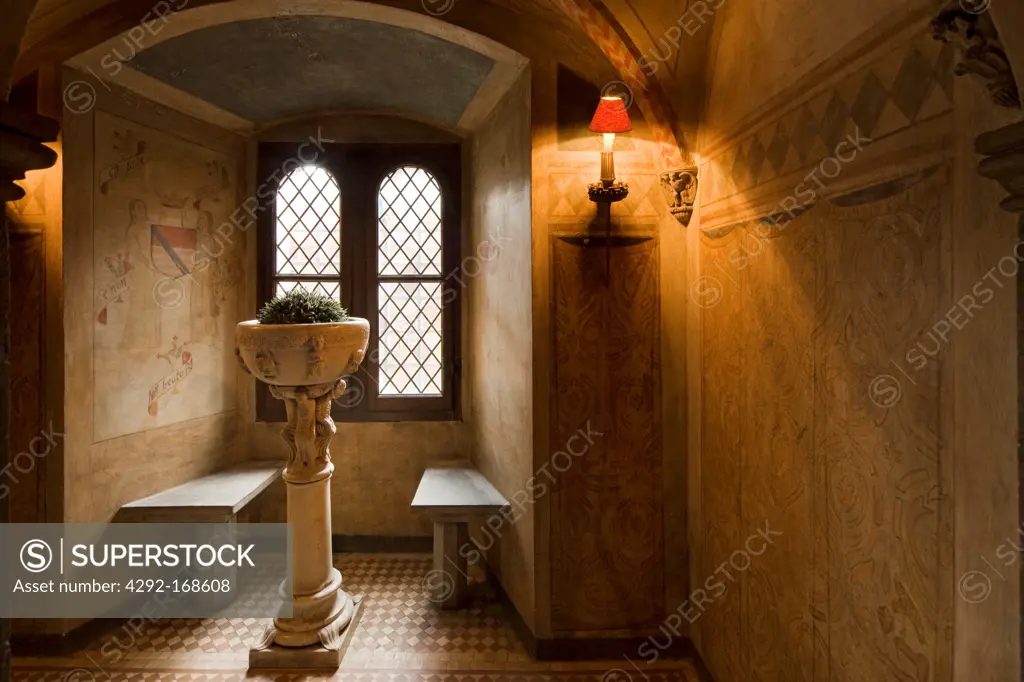 medieval room with a mullioned window and a baptismal font