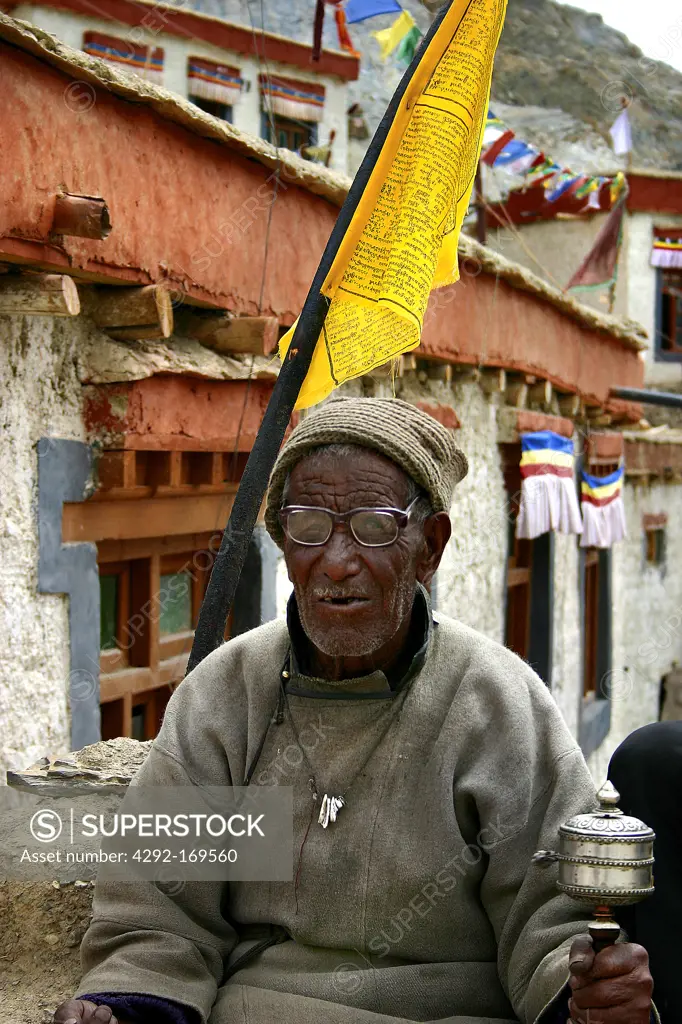 India, Ladakh, old monk with prayer wheel