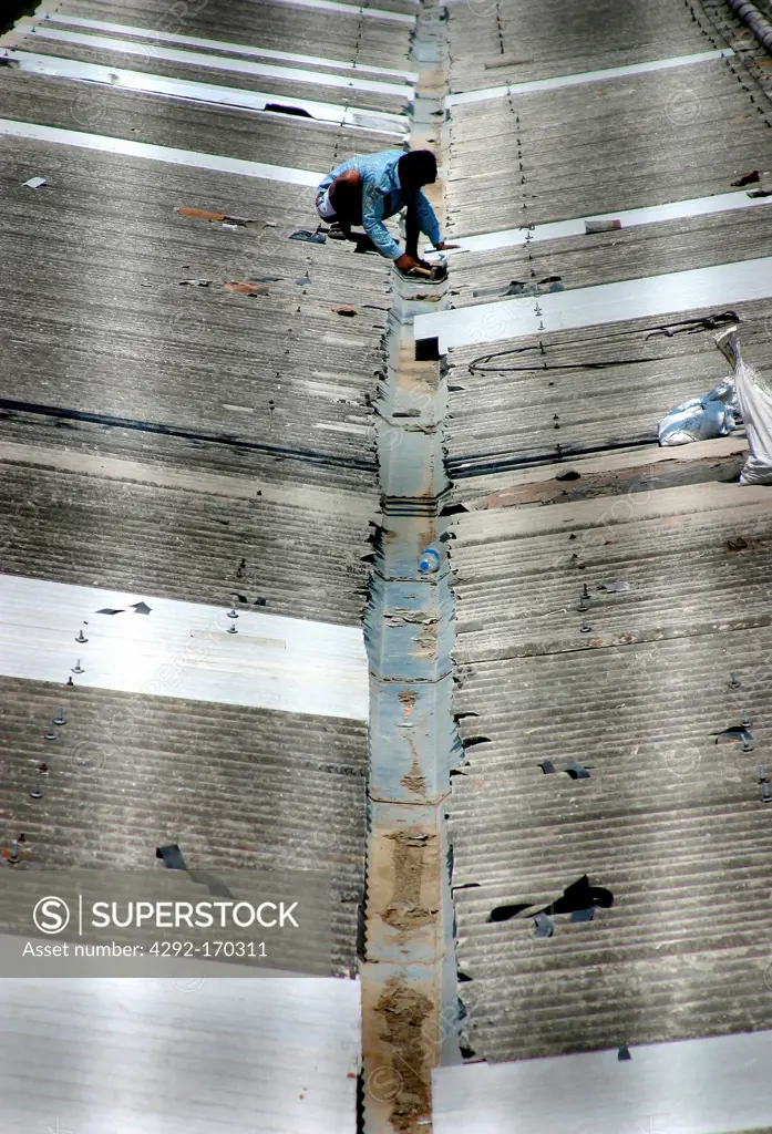 India, Delhi, man working on roof