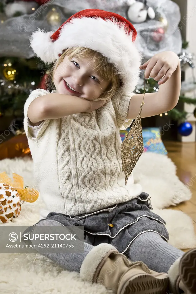 little girl sitting on a rug wearing santa claus hat
