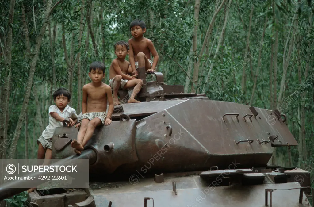 Vietnam, children clibing old tank