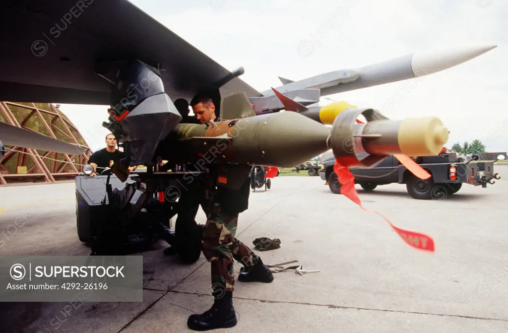 US Air Force, airman mounting GBU bomb on warplane wing pilon