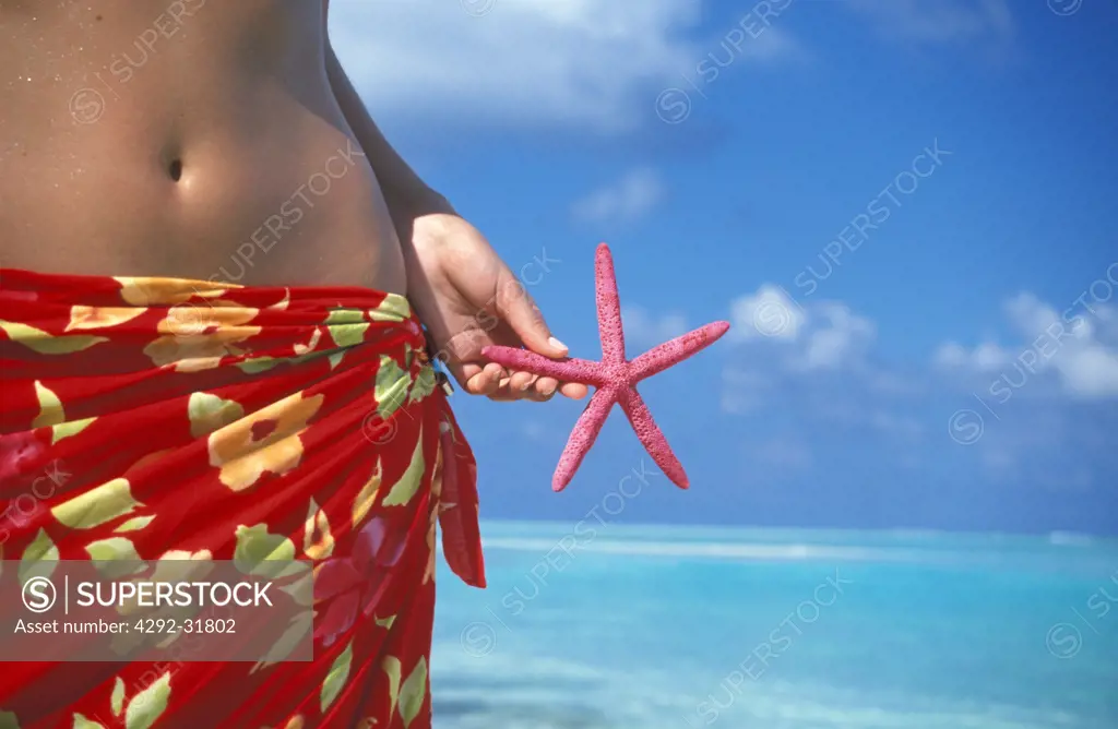 Maldives, Ari Atoll, White Sands Island, woman on beach with starfish in her hand