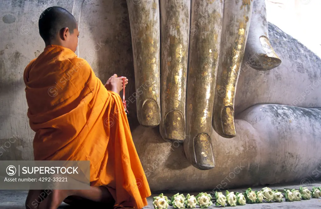 Thailand, Sukhothai, novice monk praying Buddah at Temple Wat Sri Chum